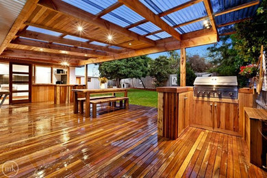 Large country backyard deck in Melbourne with an outdoor kitchen and a pergola.