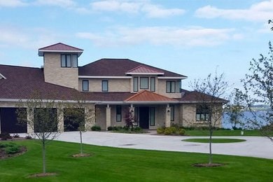 Mid-sized elegant beige two-story stone exterior home photo in Other with a hip roof