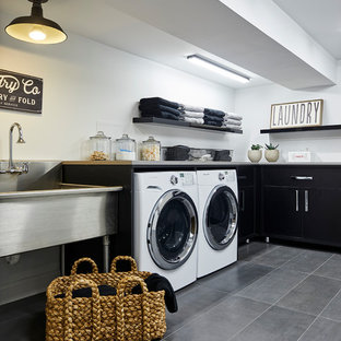 Design ideas for a large contemporary l-shaped separated utility room in New York with an utility sink, flat-panel cabinets, black cabinets, white walls, porcelain flooring, a side by side washer and dryer and grey floors.