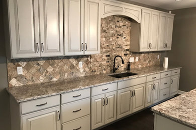 Open concept kitchen - dark wood floor open concept kitchen idea in St Louis with an undermount sink, raised-panel cabinets, beige cabinets, granite countertops, multicolored backsplash, stone tile backsplash, stainless steel appliances and an island
