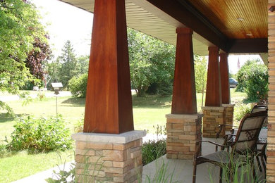 Design ideas for a mid-sized arts and crafts front yard verandah in Milwaukee with concrete slab and a roof extension.