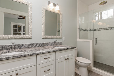 Bathroom - mid-sized craftsman 3/4 black tile, gray tile, white tile and marble tile ceramic tile and beige floor bathroom idea in Raleigh with white cabinets, a one-piece toilet, blue walls, a drop-in sink and marble countertops