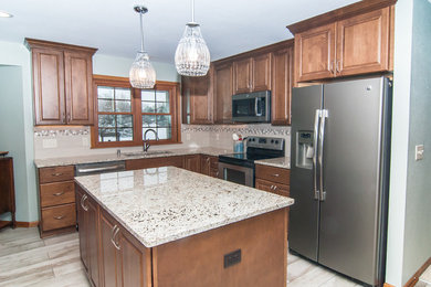 Traditional eat-in kitchen in Milwaukee with an undermount sink, raised-panel cabinets, medium wood cabinets, quartzite benchtops, beige splashback, mosaic tile splashback, stainless steel appliances, porcelain floors, with island, grey floor and beige benchtop.