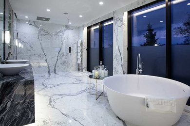 This is an example of a large contemporary master bathroom in Miami with a freestanding tub, white tile, marble, marble benchtops and black benchtops.