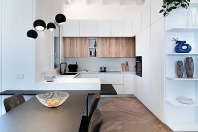 Esempio di una cucina nordica di medie dimensioni con lavello da incasso, ante a filo, ante bianche, paraspruzzi bianco, elettrodomestici neri, pavimento in gres porcellanato, penisola, pavimento beige, top bianco e travi a vista