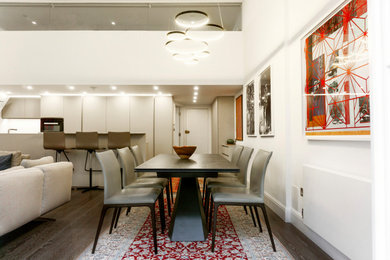 Medium sized modern open plan dining room in London with brown floors.