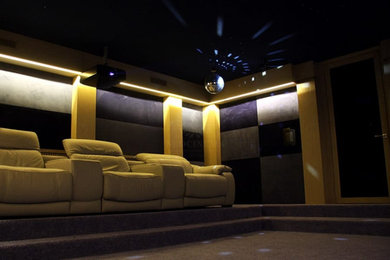 Стильный дизайн: изолированный домашний кинотеатр в современном стиле с ковровым покрытием, проектором и бежевым полом - последний тренд