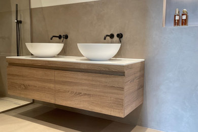 Medium sized modern bathroom in London with flat-panel cabinets, medium wood cabinets, brown walls, concrete flooring, a vessel sink, engineered stone worktops, brown floors, an open shower, white worktops, a wall niche, double sinks and a floating vanity unit.