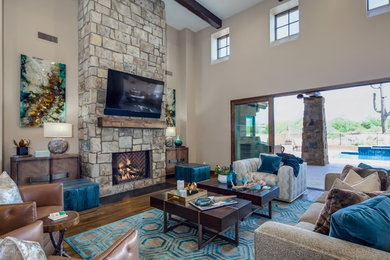Design ideas for a large eclectic open concept living room in Phoenix with beige walls, medium hardwood floors, a standard fireplace, a stone fireplace surround, a wall-mounted tv and brown floor.