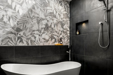 Mid-sized contemporary 3/4 bathroom in Melbourne with open cabinets, a freestanding tub, a curbless shower, a wall-mount toilet, black tile, porcelain tile, black walls, porcelain floors, an integrated sink, solid surface benchtops, black floor, an open shower, white benchtops, a niche, a single vanity and a freestanding vanity.