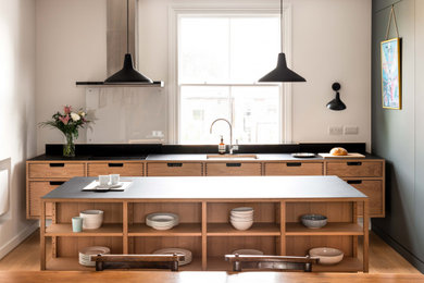 Inspiration for a small modern single-wall open plan kitchen in Other with composite countertops, black splashback, medium hardwood flooring, an island and black worktops.