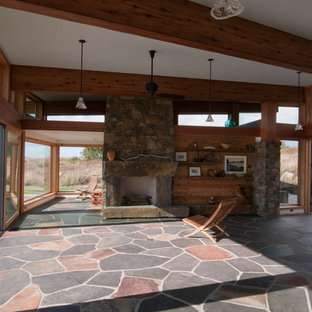 Esempio di un piccolo soggiorno contemporaneo aperto con pavimento in ardesia, camino classico, cornice del camino in pietra e nessuna TV