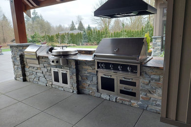 Patio kitchen - mid-sized craftsman backyard concrete paver patio kitchen idea in Seattle with a roof extension