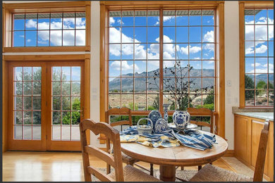 Example of a large arts and crafts medium tone wood floor and brown floor dining room design in Albuquerque with white walls, a standard fireplace and a stone fireplace