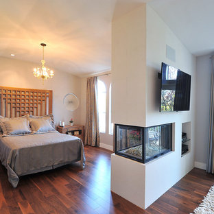 Modernes Hauptschlafzimmer mit beiger Wandfarbe, dunklem Holzboden und Tunnelkamin in Los Angeles