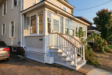 Small screened-in and wood railing front porch idea in Burlington with decking and a roof extension