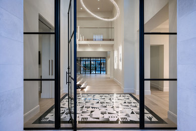 Inspiration for a huge modern light wood floor and multicolored floor entryway remodel in Phoenix with white walls and a black front door