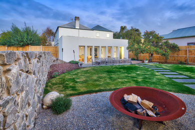 Modern backyard garden in Melbourne with a fire feature and gravel.