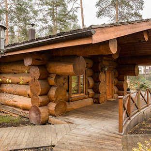 Пример оригинального дизайна интерьера: одноэтажный фасад частного дома среднего размера коричневого цвета в стиле рустика с облицовкой из дерева и двускатной крышей