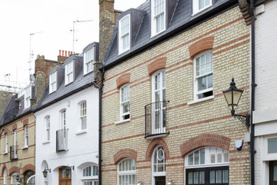 Inspiration for a medium sized and yellow bohemian brick house exterior in London with four floors, a mansard roof and a grey roof.