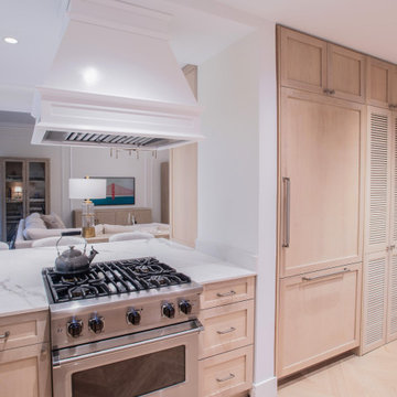 Transitional kitchen with marble countertops, custom hood, and integrated refrig