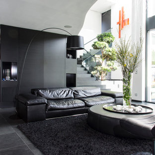 Inredning av ett modernt stort allrum med öppen planlösning, med skiffergolv, en väggmonterad TV och svarta väggar