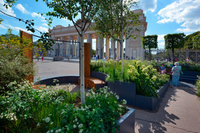 На фото: большой летний регулярный сад на переднем дворе в современном стиле с высокими грядками, полуденной тенью и мощением тротуарной плиткой с