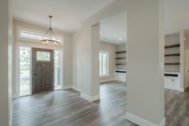 Example of a large arts and crafts medium tone wood floor and brown floor entryway design in Calgary with beige walls and a dark wood front door