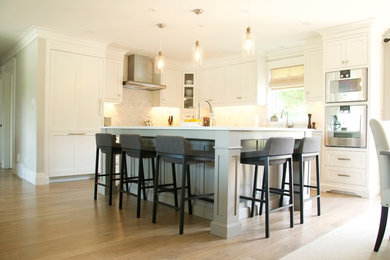 Inspiration for a large transitional l-shaped light wood floor eat-in kitchen remodel in Toronto with shaker cabinets, white cabinets, gray backsplash, subway tile backsplash, stainless steel appliances and an island