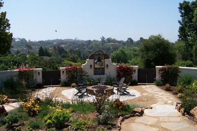 This is an example of a large southwestern full sun and drought-tolerant backyard stone landscaping in San Diego with a fire pit for summer.