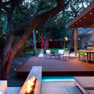 На фото: большие дворики на заднем дворе в современном стиле с местом для костра и настилом