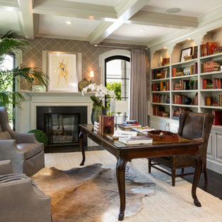 This is an example of an arts and crafts study room in Los Angeles with beige walls, dark hardwood floors, a standard fireplace, a wood fireplace surround and a freestanding desk.