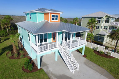 Beach style three-storey orange house exterior in Las Vegas with concrete fiberboard siding, a hip roof and a metal roof.