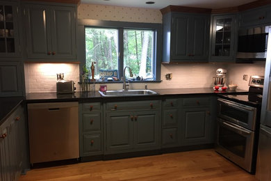 Inspiration for a mid-sized timeless u-shaped medium tone wood floor and brown floor eat-in kitchen remodel in New York with a drop-in sink, raised-panel cabinets, blue cabinets, granite countertops, white backsplash, ceramic backsplash, stainless steel appliances, a peninsula and black countertops