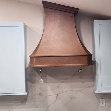 Handcrafted Copper Range Hood Framed by Soft Blue Cabinetry