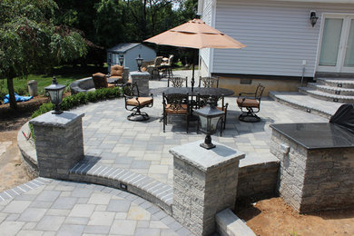 Photo of a backyard patio in New York with a fire feature and brick pavers.