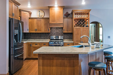 Inspiration for a mid-sized craftsman l-shaped medium tone wood floor and brown floor eat-in kitchen remodel in Columbus with an undermount sink, shaker cabinets, medium tone wood cabinets, granite countertops, black backsplash, ceramic backsplash, stainless steel appliances and an island