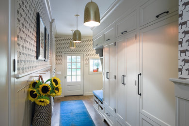 This is an example of a large transitional mudroom in New York with brown walls, porcelain floors, a single front door and a black front door.
