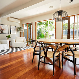 タウンズビルの中サイズのトロピカルスタイルのLDKの画像 (白い壁、無垢フローリング、木材の暖炉まわり、茶色い床)