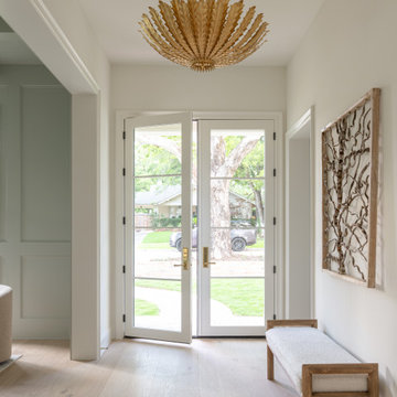 Light-filled foyer with French doors, gold leaf chandelier, and white oak