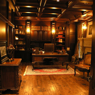 Foto på ett mellanstort vintage hemmabibliotek, med beige väggar, mellanmörkt trägolv, en standard öppen spis, en spiselkrans i gips, ett fristående skrivbord och brunt golv