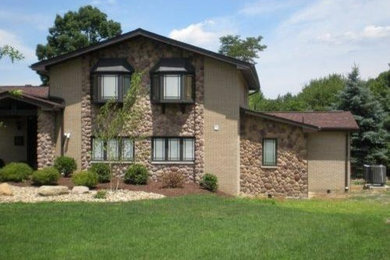 Inspiration for a mid-sized timeless beige two-story brick gable roof remodel in Other
