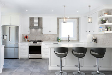 Photo of a transitional u-shaped kitchen in Toronto with an undermount sink, shaker cabinets, white cabinets, grey splashback, stainless steel appliances, a peninsula, grey floor and grey benchtop.