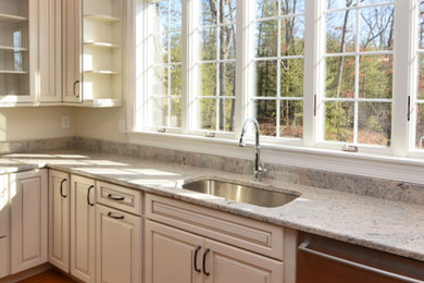Huge elegant u-shaped brown floor eat-in kitchen photo in Boston with an undermount sink, raised-panel cabinets, white cabinets, granite countertops, stainless steel appliances and an island