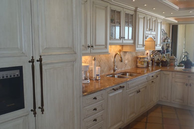 Inspiration for a large coastal ceramic tile and brown floor eat-in kitchen remodel in Miami with a double-bowl sink, raised-panel cabinets, white cabinets, granite countertops, beige backsplash, ceramic backsplash and paneled appliances