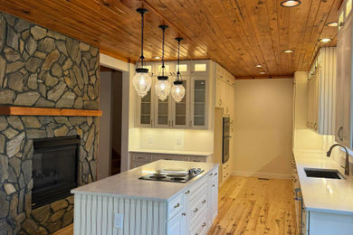 Example of a large arts and crafts galley light wood floor and wood ceiling kitchen pantry design in Raleigh with raised-panel cabinets, white cabinets, an island and white countertops