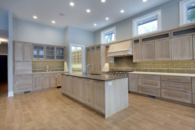 Inspiration for a huge coastal l-shaped porcelain tile open concept kitchen remodel in Grand Rapids with an undermount sink, recessed-panel cabinets, light wood cabinets, quartz countertops, gray backsplash, stone tile backsplash, paneled appliances and an island