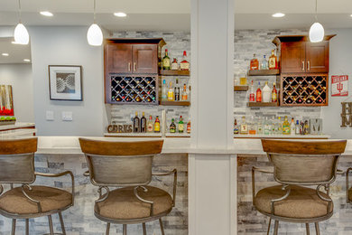 Inspiration for a large transitional l-shaped brown floor wet bar remodel in Chicago with an undermount sink, recessed-panel cabinets, white cabinets, quartzite countertops, gray backsplash, stone tile backsplash and white countertops