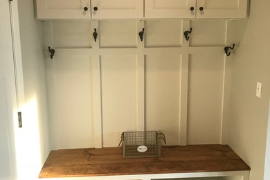 Laundry room - farmhouse laundry room idea in St Louis with flat-panel cabinets, white cabinets and wood countertops