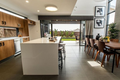 Photo of a mid-sized modern single-wall eat-in kitchen in Brisbane with an undermount sink, flat-panel cabinets, medium wood cabinets, granite benchtops, window splashback, stainless steel appliances, cement tiles and with island.